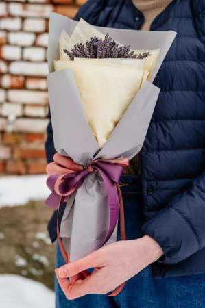 Beautiful bouquet of lavender in gray and yellow packaging in hands of womanの写真素材