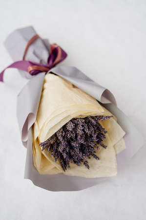 Beautiful bouquet of lavender in gray and yellow packaging on white snowの写真素材