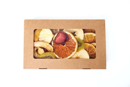 Mix dried fruits in craft paper rectangular box with transparent lid on white background. Vegetarian lifestyle.の写真素材