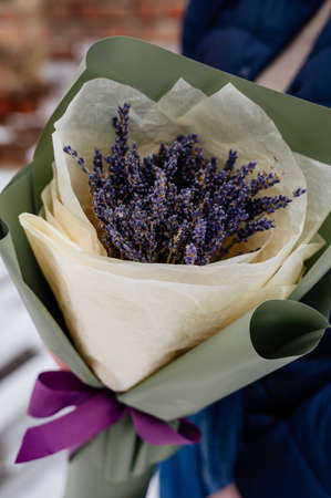 Beautiful bouquet of lavender in green and yellow packaging in hands of womanの写真素材