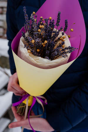 Small beautiful bouquet of lavender in yellow-purple packaging in hands of womanの写真素材