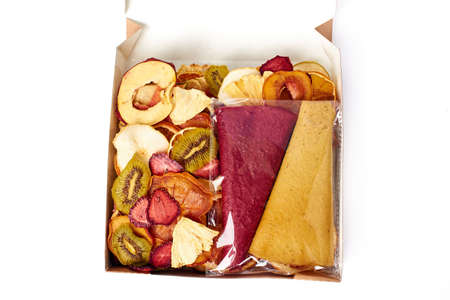 Mix dried fruits and mix fruit pastille marshmallow in open craft paper square box on white background. Vegetarian lifestyle.の写真素材