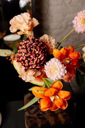 Bouquet of flowers with tulip, dahlia, chrysanthemum, eustoma in orange tones on dark backgroundの写真素材