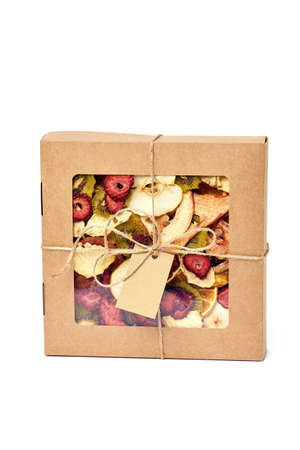 Mix dried fruits in craft paper square box with transparent lid with twine ribbon on white background. Vegetarian lifestyle.の写真素材