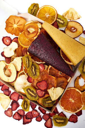 Scattered mix dried fruits and mix fruit pastille marshmallow in open craft paper square box on white background. Vegetarian lifestyle.の写真素材