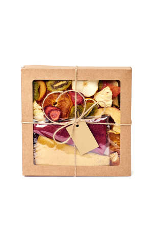 Mix dried fruits in craft paper square box with transparent lid with twine ribbon on white background. Vegetarian lifestyle.の写真素材