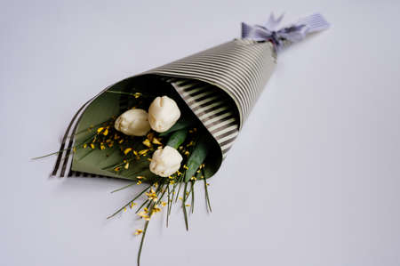 Bouquet of white tulips in striped black and pistachio-colored package on white background.の写真素材