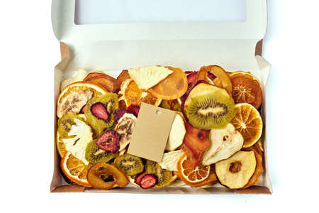Mix dried fruits in open craft paper rectangular box with transparent lid with twine ribbon and card on white background. Vegetarian lifestyle.の写真素材