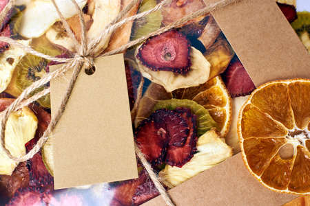 Close-up mix dried fruits in craft paper square box with transparent lid with twine ribbon on mix dried fruits background on white background. Vegetarian lifestyle.の写真素材