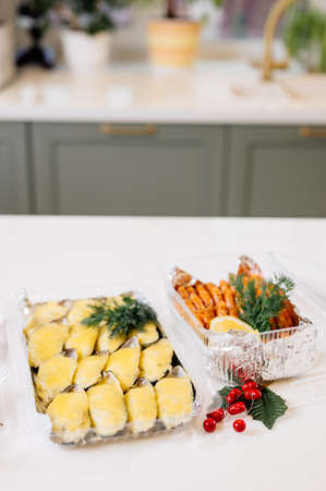 Mussels in shells baked with cheese in a plastic box and fried shrimps in a plastic box and red berries on kitchen tableの写真素材