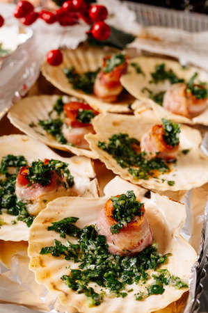 Luxury sea scallop in shell with bacon and herbs close-up. In background are red berries.の写真素材
