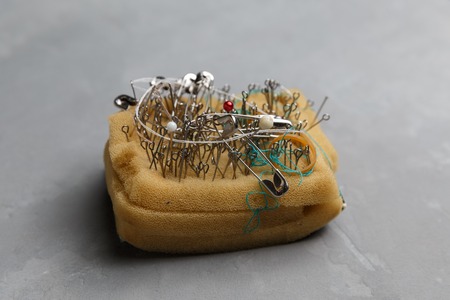Pin cushion with sewing pins on the grey concrete background