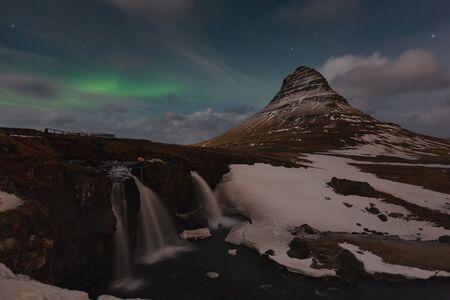 Famous mountain with waterfalls in Iceland, aurora borealis, night, kirkjufell, winter in Iceland, ice and snow, reflections, yellow grass, nature, icelandic famous landscapeの写真素材