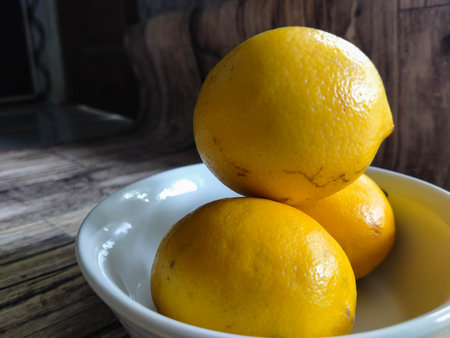 Lemons in a white bowl on a wooden table. Close-up.の写真素材