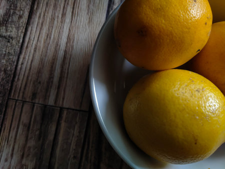 Close up of fresh oranges in a bowl on a wooden table.