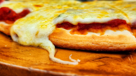 Pizza with cheese, tomato and mozzarella on a wooden boardの写真素材