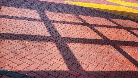 The shadow of the metal fence on the red brick pavement in the park.の写真素材