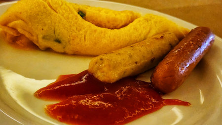 Omelet with sausages and tomato sauce on a plateの写真素材