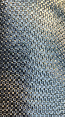 Background of black carbon fiber with small holes in the form of square tilesの写真素材
