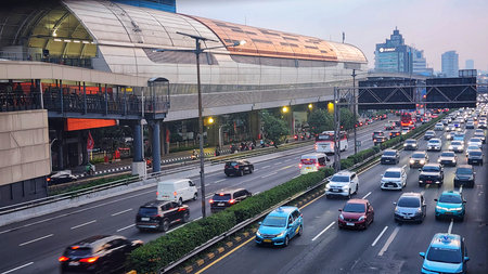 Evening traffic on a Jakarta highway with an elevated train stationの写真素材