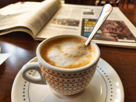 A cup of coffee in front of an open newspaper on a table in a cafe, Nava, Asturias, Spainの写真素材