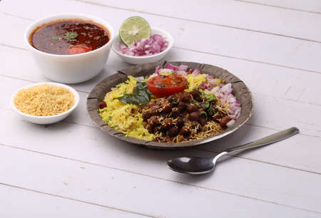 Aloo/Kanda Poha or Tarri Pohe with spicy chana masala/curry. Served in ceramic plate.