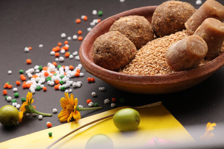 Til Gul OR Sweet Sesame Laddu with Kite model, haldi Kumkum and sugar crystals for Makar Sankranti festival over black background.の写真素材