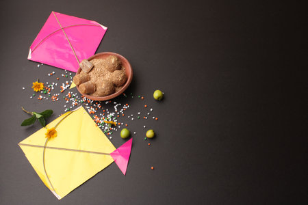 Til Gul OR Sweet Sesame Laddu with Kite model, haldi Kumkum and sugar crystals for Makar Sankranti festival over black background.の写真素材
