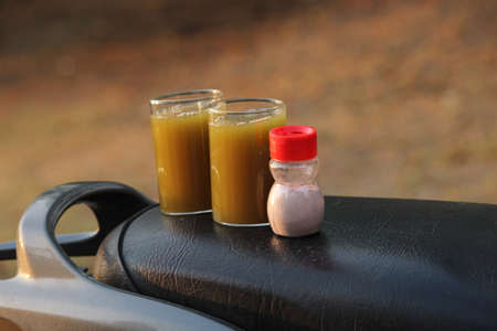 Sugarcane juice in glass with piece of sugarcane, lemon and black saltの写真素材