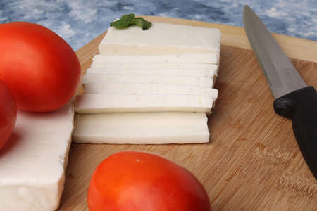 sliced fresh paneer or cottage cheese with tomatoes and knife on cutting board.の写真素材