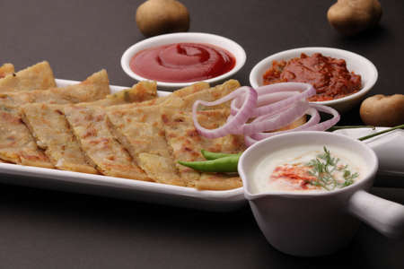 Traditional Indian food Aloo paratha or potato stuffed flat bread. served with pickle tomato ketchup and curd, butter, onion chili.の写真素材
