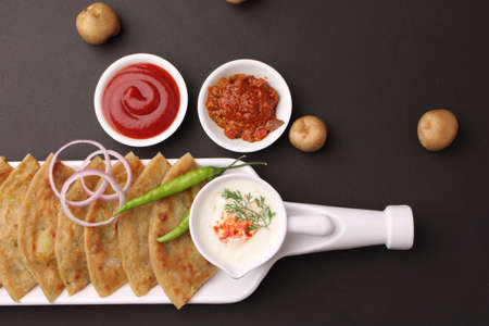 Traditional Indian food Aloo paratha or potato stuffed flat bread. served with pickle tomato ketchup and curd, butter, onion chili.の写真素材