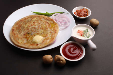 Traditional Indian food Aloo paratha or potato stuffed flat bread. served with pickle tomato ketchup and curd,の写真素材
