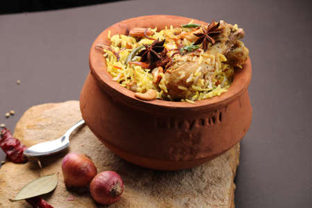 Spicy chicken biryani in traditional handi or clay pot. served with onion raitaの写真素材