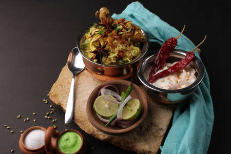 chicken dum biriyani served in copper handi or bowl with onion raita.の写真素材