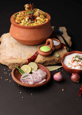 Spicy chicken biryani in traditional handi or clay pot. served with onion raitaの写真素材