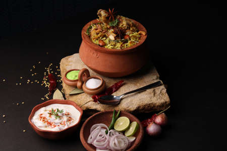 Spicy chicken biryani in traditional handi or clay pot. served with onion raitaの写真素材