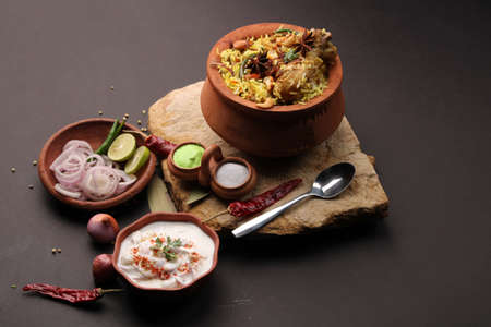 Spicy chicken biryani in traditional handi or clay pot. served with onion raitaの写真素材