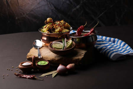 chicken dum biriyani served in copper handi or bowl with onion raita.の写真素材