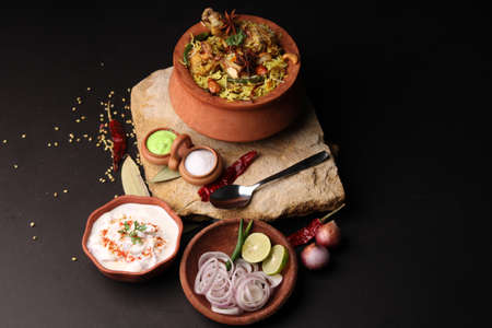 Spicy chicken biryani in traditional handi or clay pot. served with onion raitaの写真素材