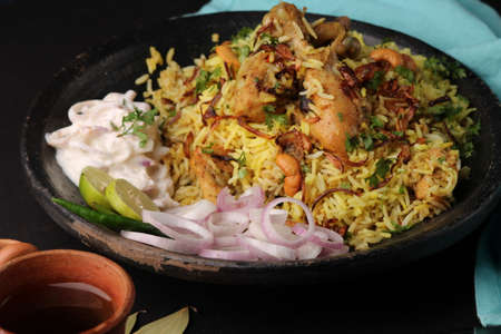 chicken dum biriyani served in earthen  plate with onion raita.の写真素材