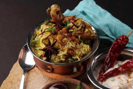 chicken dum biriyani served in copper handi or bowl with onion raita.の写真素材
