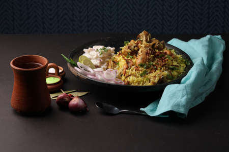 chicken dum biriyani served in earthen  plate with onion raita.の写真素材