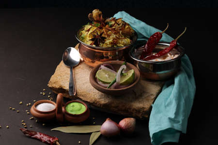 chicken dum biriyani served in copper handi or bowl with onion raita.の写真素材