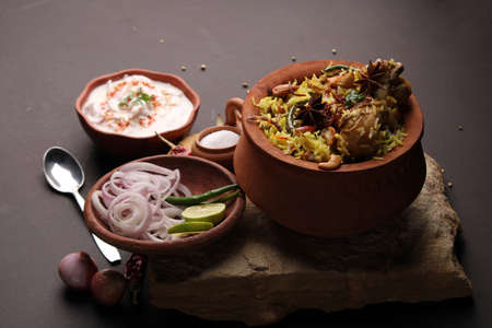 Spicy chicken biryani in traditional handi or clay pot. served with onion raitaの写真素材