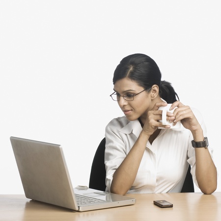Businesswoman working on a laptop and drinking coffeeの写真素材