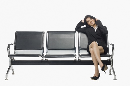 Businesswoman sitting on an armchair and talking on a mobile phoneの写真素材