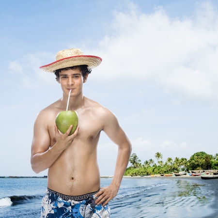 Man drinking coconut milk on the beachの写真素材