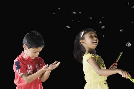 Girl blowing bubbles and a boy looking at his palm