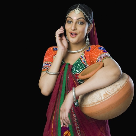 Beautiful woman in colorful lehenga choli carrying water pot